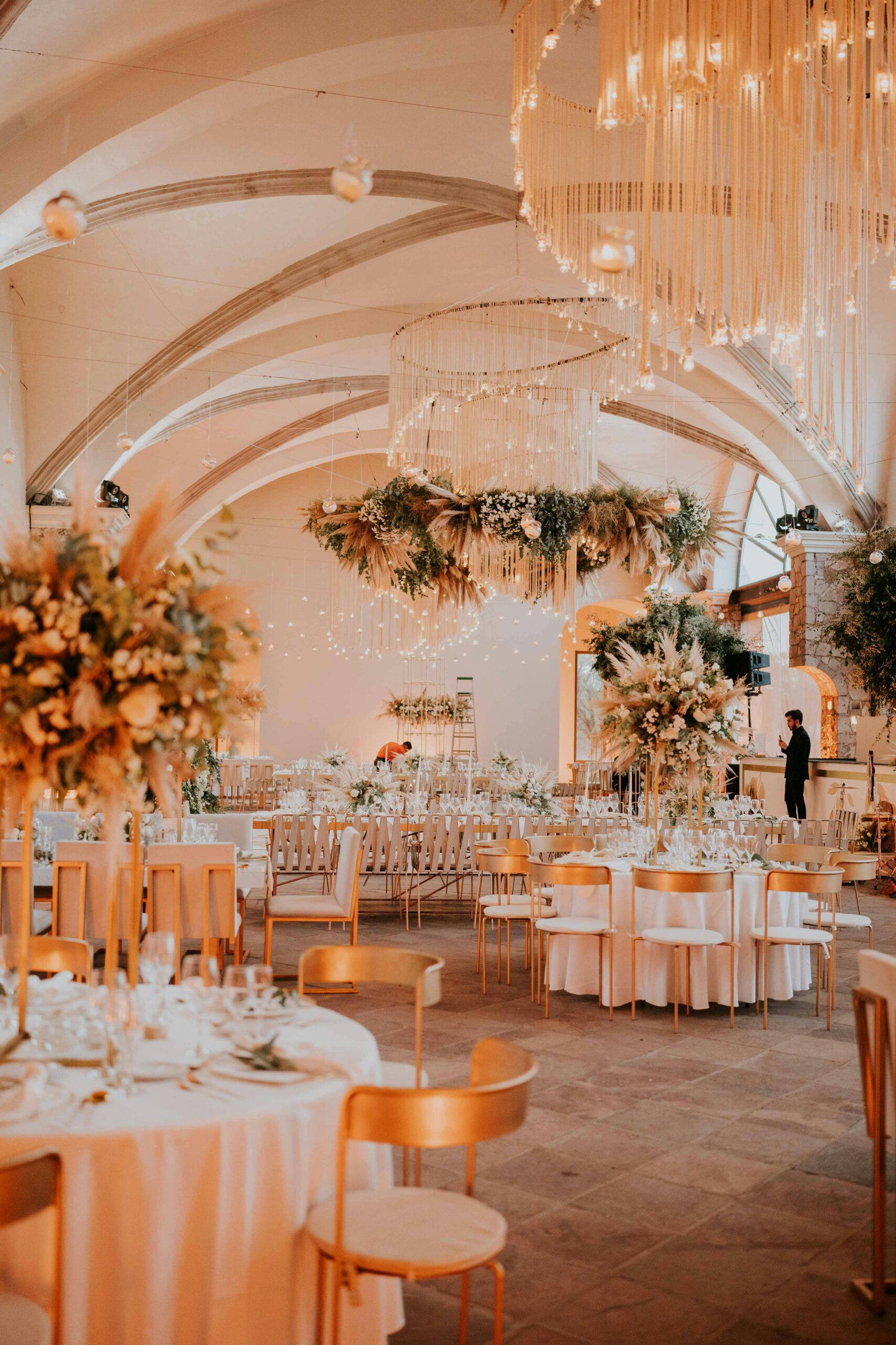 Stunning wedding reception setup with white tablecloths and floral chandeliers in an elegant indoor venue.